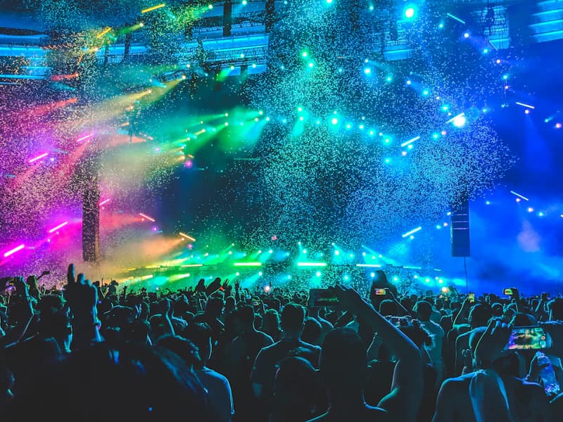 Concert crowd with raised hands under stage lights