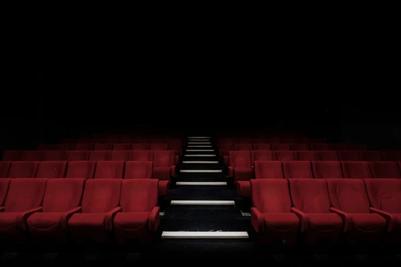 Rows of red cinema seats in a dark theatre
